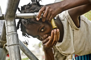 Una niña bebe agua en un punto de distribución del campo de desplazados de la Universite de Quisqueya en Puerto Príncipe. (c) Pablo Tosco / Intermón Oxfam
